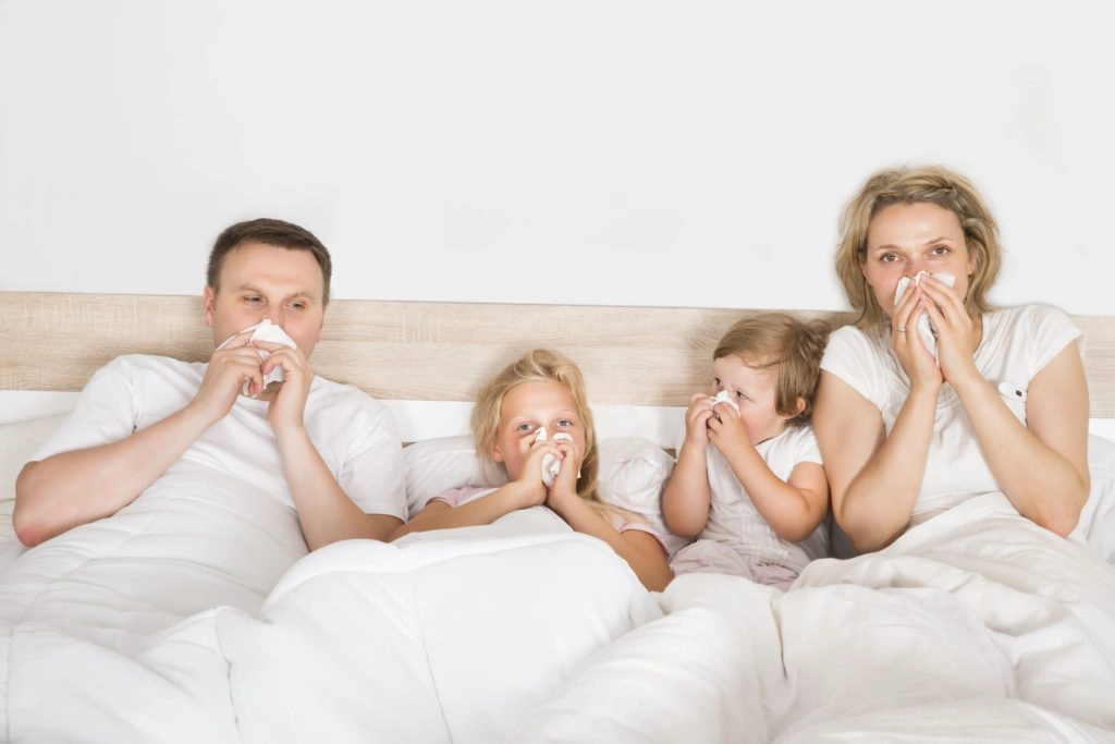 Familie liegt mit Grippe im Bett