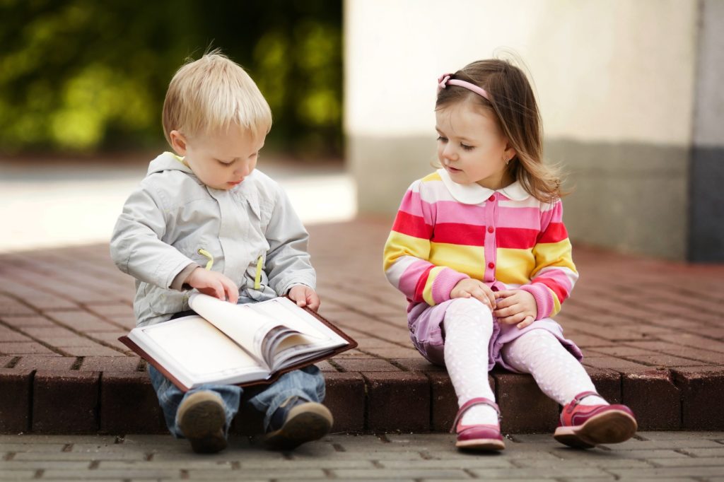 zwei Kleinkinder schauen sich ein Buch an