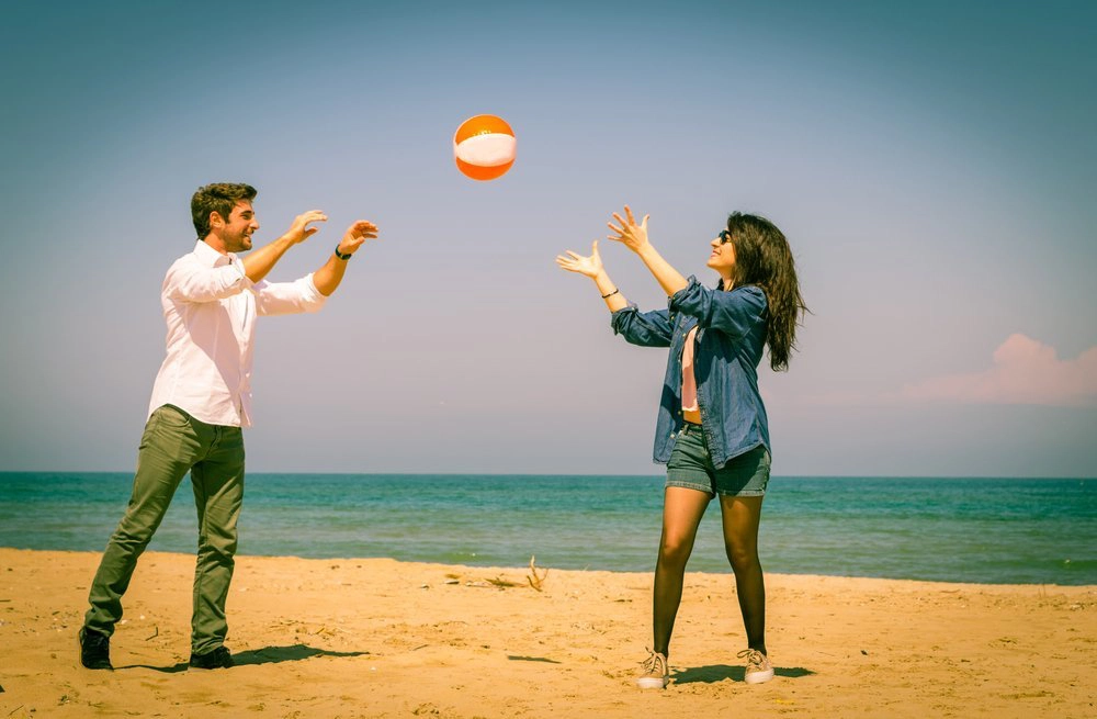 Mann und Frau spielen Ball am Strand 